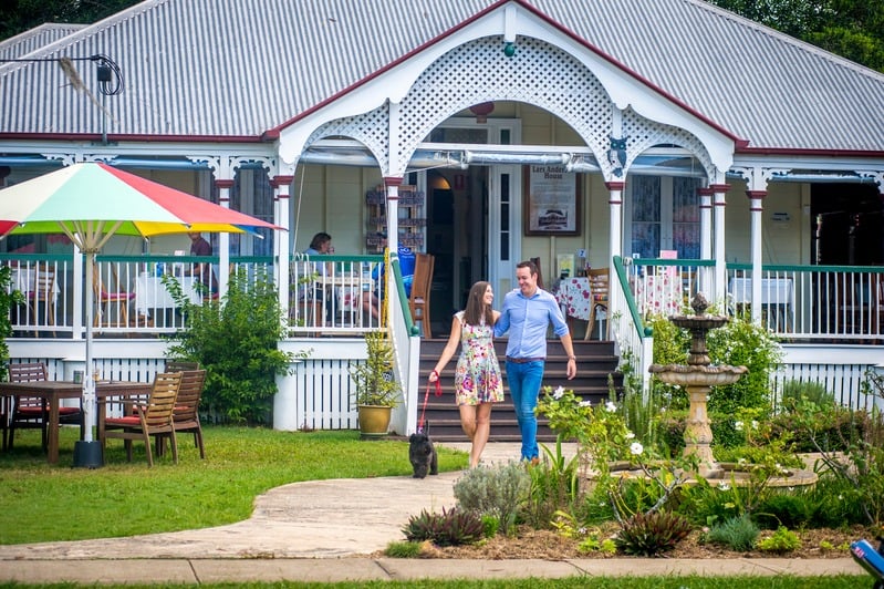 A couple walking a dog towards a heritage hinterland building