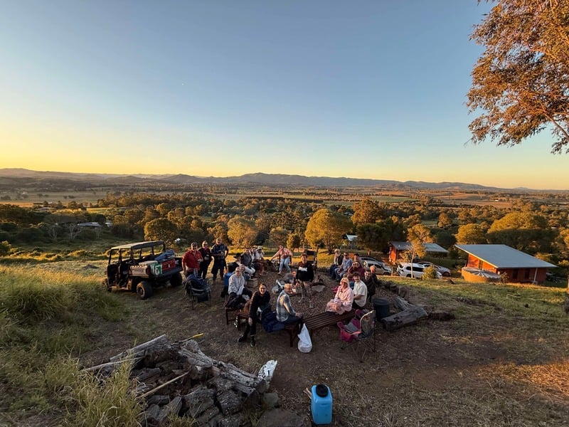 Guests gathered around the fire pit at sunset with panoramic views
